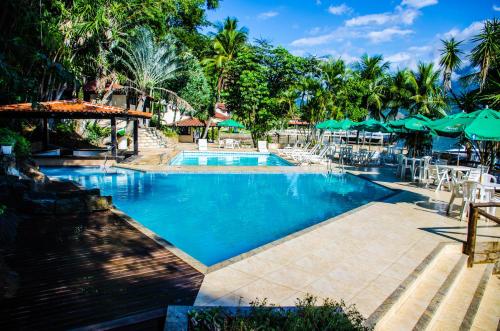 una piscina en un complejo con mesas y sombrillas en Hotel Pierre, en Itaguaí