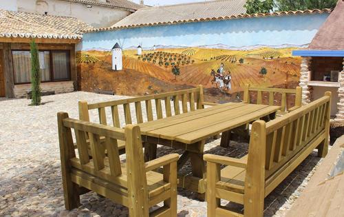 a wooden table and benches in front of a mural at Casa Rural La Tia Lola in Puerto Lápice