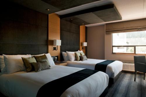 a hotel room with two beds and a window at Ramada Plaza by Wyndham Prince George in Prince George