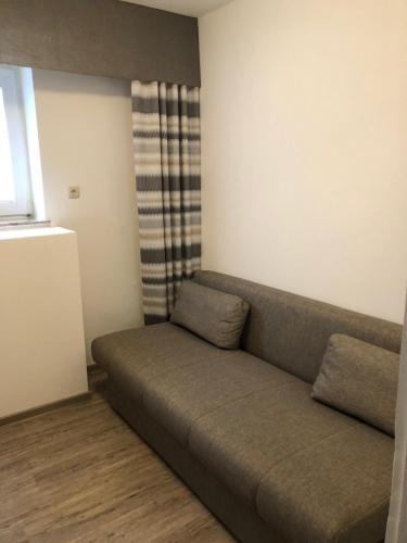 a couch sitting in a living room with a window at Heeren's Hotel Garni in Bensersiel