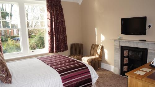 a bedroom with a bed and a fireplace and a television at The Lawn Guest House Gatwick in Horley