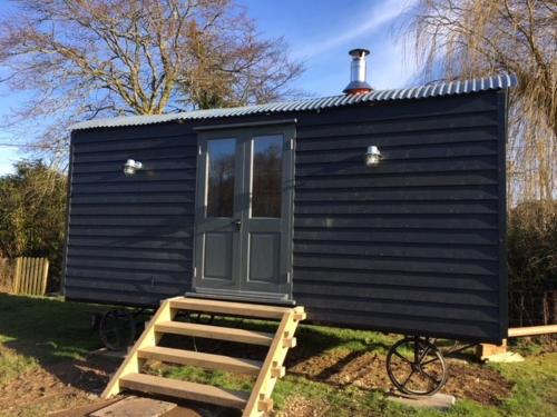 a black tiny house with a door and stairs at Hare & Hounds Bed & Breakfast in Rye
