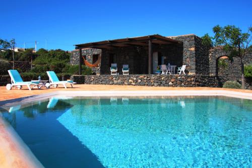 a swimming pool with two chairs and a house at Dammusi I Jardina in Pantelleria