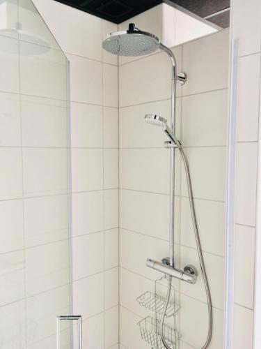 a shower with a shower head in a bathroom at Appartement aan het strand, hond welkom in Zoutelande