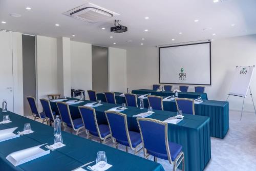 a conference room with blue tables and chairs and a screen at San Paolo Hotel in Montegiorgio