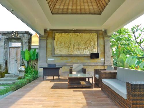 a patio with a couch and a tv on a wall at Ubud Lestari Villa in Ubud