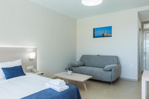 a bedroom with a bed and a couch and a chair at Sun and Sea Plus Resort in Plaka