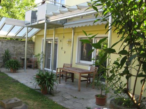 a patio with a wooden table and a yellow house at Haus Gartentraum in Sommerhausen