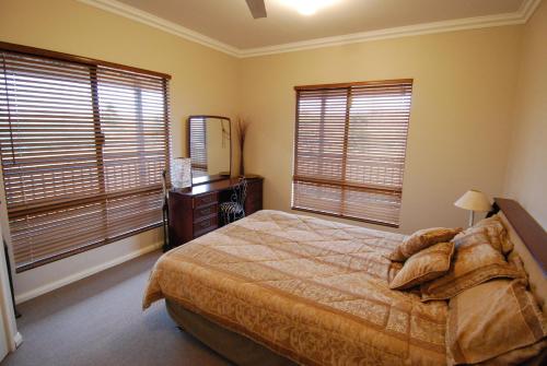 a bedroom with a bed and two large windows at Mountain Park Retreat in Perth