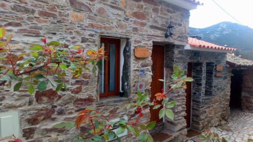 a stone building with a red door and a window at Casas dos Carregais in Carregais