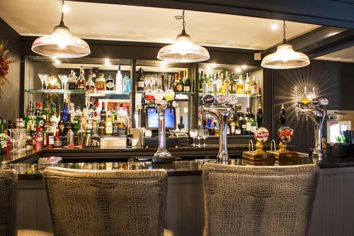 a bar with two chairs in front of a bar at The Boars Head Hotel in Sudbury