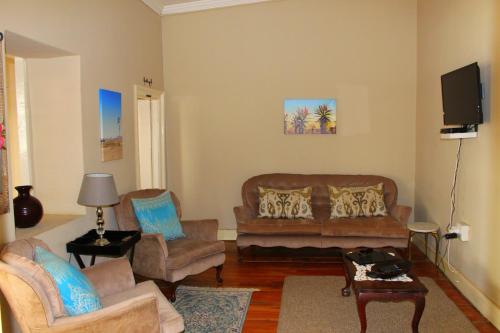 a living room with a couch and chairs and a tv at Boer & Brit in Graaff-Reinet