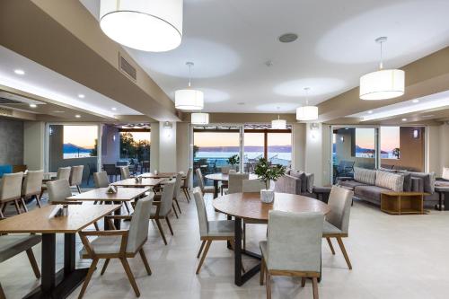 a restaurant with tables and chairs and a couch at Sun and Sea Plus Resort in Plaka