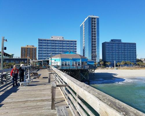 a person walking on a pier next to the beach at Yachtsman Oceanfront Resort in Myrtle Beach