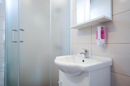 biała łazienka z umywalką i prysznicem w obiekcie Apartment Ivana w mieście Trebinje