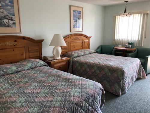 Habitación de hotel con 2 camas y mesa con lámpara en Windswept Motel, en Point Pleasant Beach
