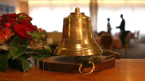 a bell on a table next to a bouquet of roses at Hotel Well Garni in Wittlich