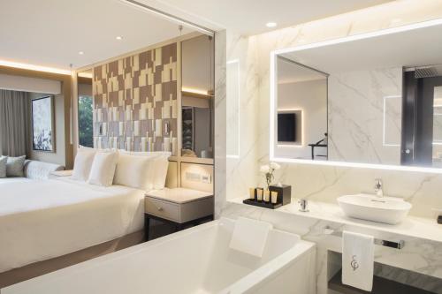 a bedroom with a bed and a sink and a mirror at El Embajador, a Royal Hideaway Hotel in Santo Domingo