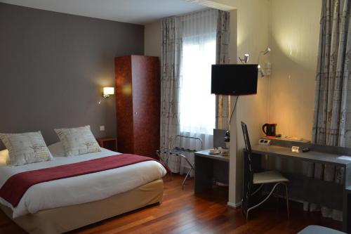 a hotel room with a bed and a desk and a window at Logis Hôtel du Centre - Halte idéale en cyclotourisme avec garage à vélos clos in Molsheim