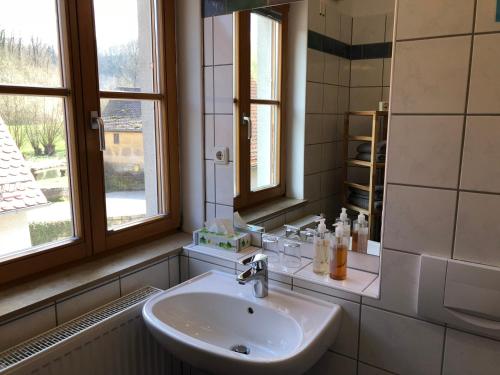 a bathroom with a sink and two windows at Fuchsmühle in Rothenburg ob der Tauber