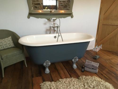 a bath tub in a bathroom with a chair and a rug at The Granary in Lifton
