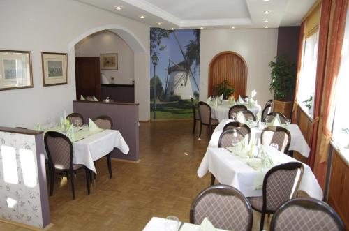 restauracja z białymi stołami i krzesłami w pokoju w obiekcie Hotel Eichenhof w mieście Klein Reken