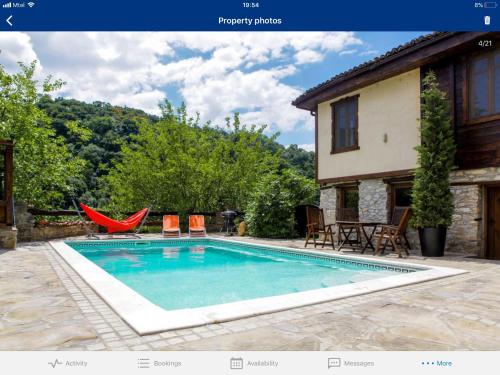 a swimming pool with chairs and a house at Veliko Tarnovo Villa Lora in Veliko Tŭrnovo