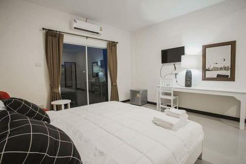 a white bedroom with a large bed and a desk at Banjan Stay in Udon Thani