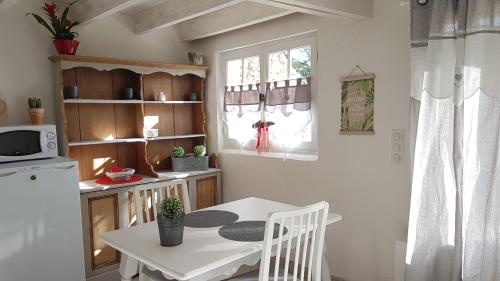 a kitchen with a white table and a small table and a microwave at Le Clos Des Etoiles in Le Bugue