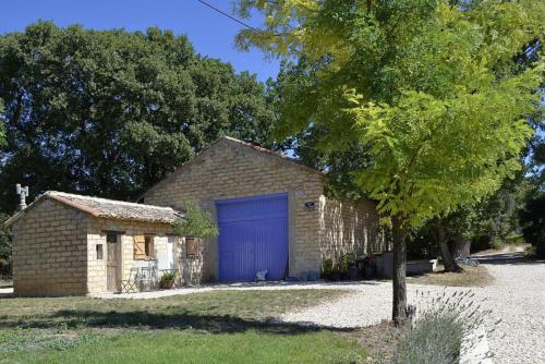 a brick garage with a blue garage door next to a tree at Masmazan in Mazan