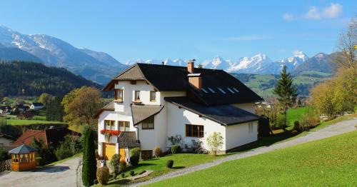 a house on a hill with mountains in the background at Haus Löger Apartments Pyhrn Priel in Windischgarsten