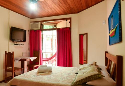 a bedroom with a bed and a window with red curtains at Pousada Recanto do Sabiá in Abraão