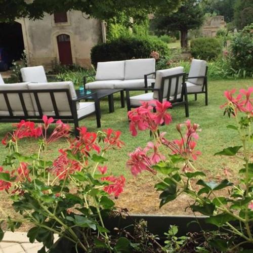 een groep stoelen en rode bloemen in een tuin bij Chateau De Mesnac in Mesnac
