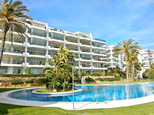 un gran edificio de apartamentos con piscina y palmeras en SkySea Holidays MI CAPRICHO, en Sitio de Calahonda