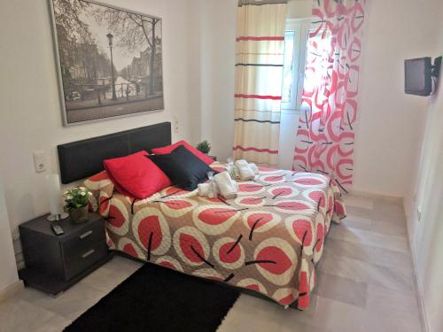 Habitación pequeña con cama con almohadas rojas en SkySea Holidays MI CAPRICHO, en Sitio de Calahonda