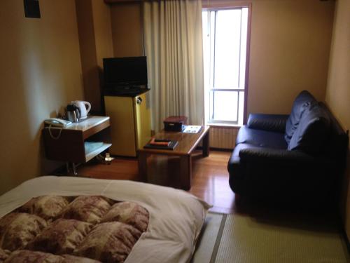 a room with a bed and a couch and a window at Hotel Edoya in Tokyo