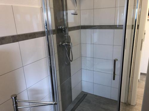 ducha con puerta de cristal y azulejos blancos en Ferienwohnung Anke - Apartement 1, en Hückelhoven