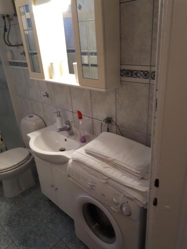 een badkamer met een wastafel, een toilet en een spiegel bij Villa Iris in Šibenik