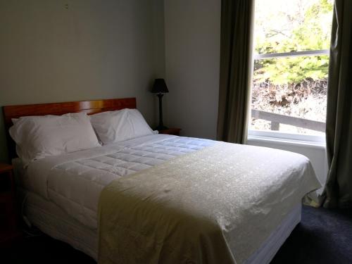a bedroom with a white bed with a window at Driftwood Villa in Kaikoura