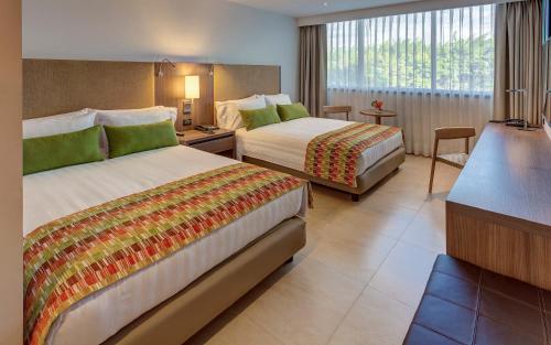 um quarto de hotel com duas camas e uma secretária em Estelar Villavicencio Hotel & Centro De Convenciones em Villavicencio