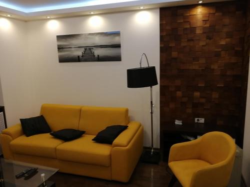 uma sala de estar com um sofá amarelo e duas cadeiras em Leon em Gornji Milanovac