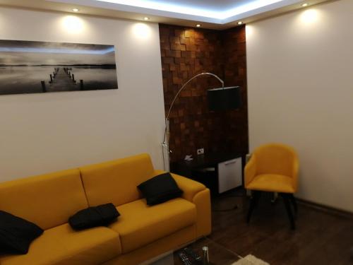uma sala de estar com um sofá amarelo e uma cadeira em Leon em Gornji Milanovac