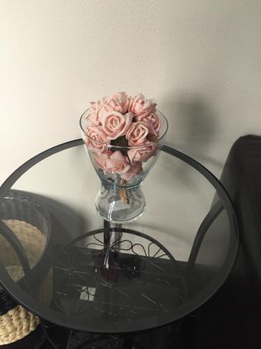 a glass vase with pink roses on a glass table at Амир in Gagra