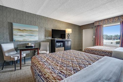 a hotel room with two beds and a desk and a television at Blue Creek Inn in Waretown