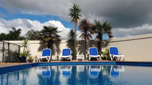 a group of blue chairs sitting next to a swimming pool at Bay Palm Motel in Mount Maunganui