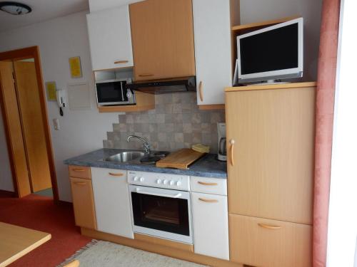 a kitchen with a stove and a tv on top of it at Apart-Alpin in Stanzach