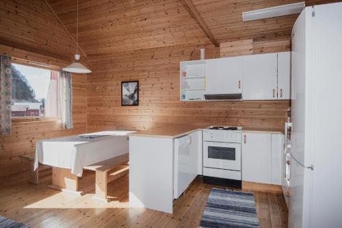 a kitchen with white appliances and a wooden wall at Grandane Feriehus in Stongfjorden