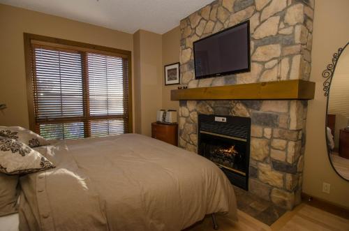 a bedroom with a fireplace with a tv above it at Luxurious Equinoxe Ski-in/Ski-out in Mont-Tremblant