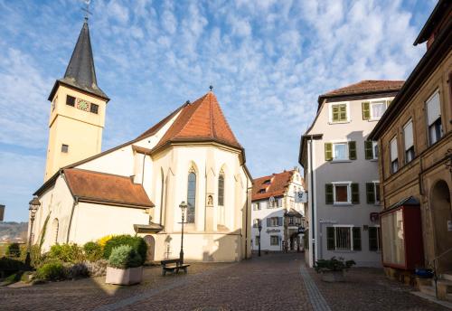 une église avec une tour d'horloge à côté de deux bâtiments dans l'établissement FeWo Gundelsheim, à Gundelsheim