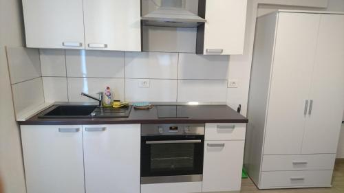 a kitchen with white cabinets and a sink at Apartment Grosek in Pobegi